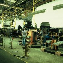 Men working underneath the moving production line of Transits, suspended on the monorail 2005.